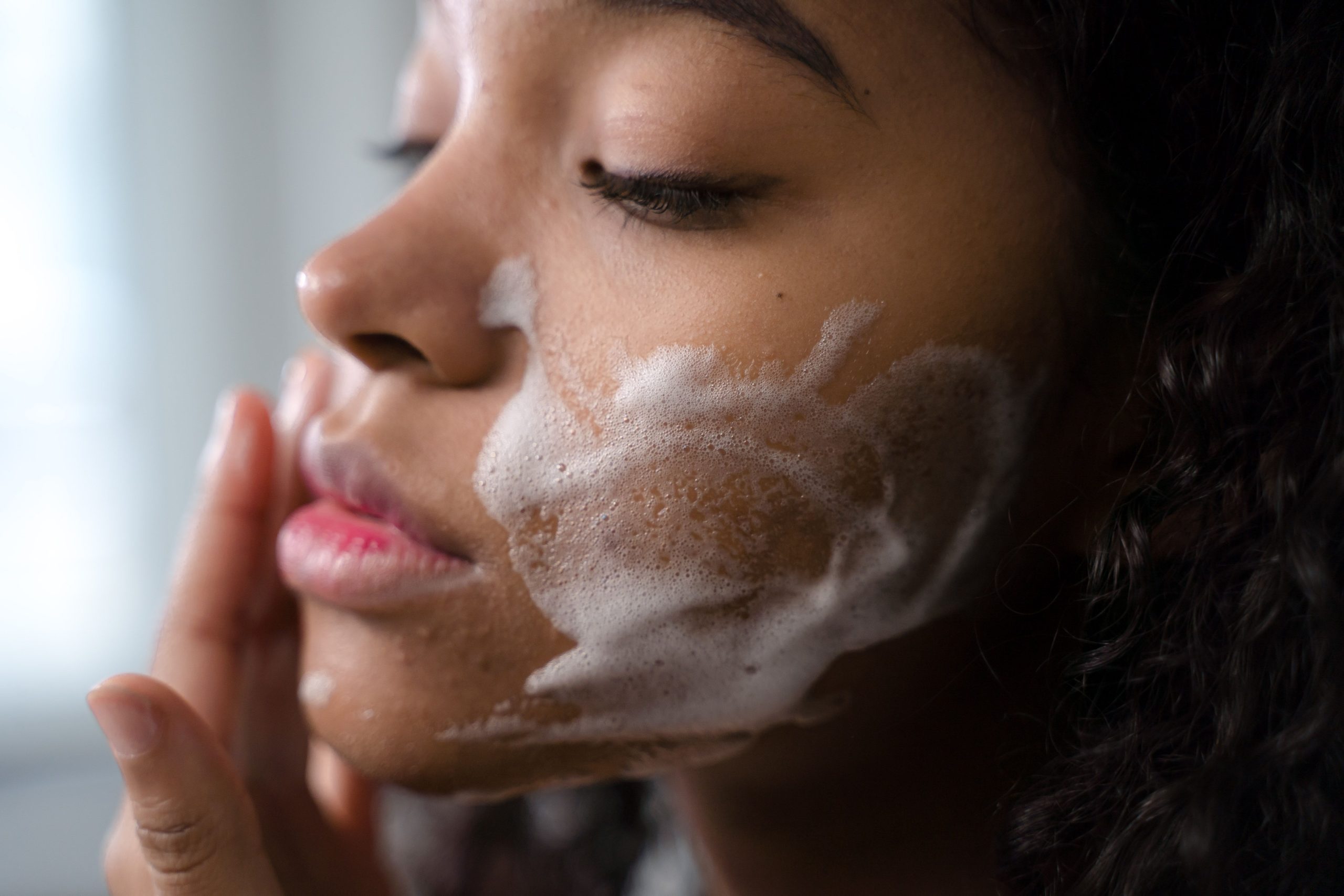 Femme appliquant mousse nettoyante sur son visage