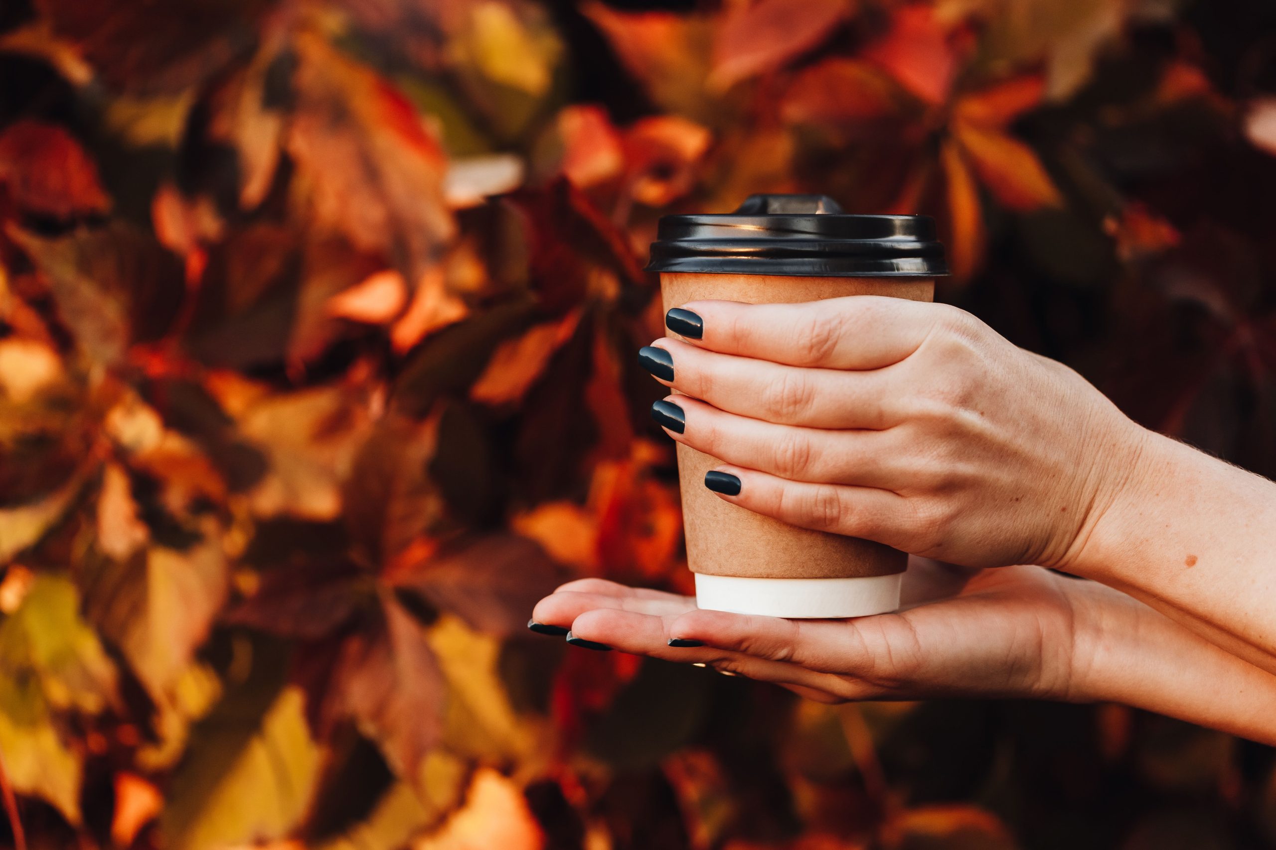 Ongles noirs tenant une tasse de café automne.