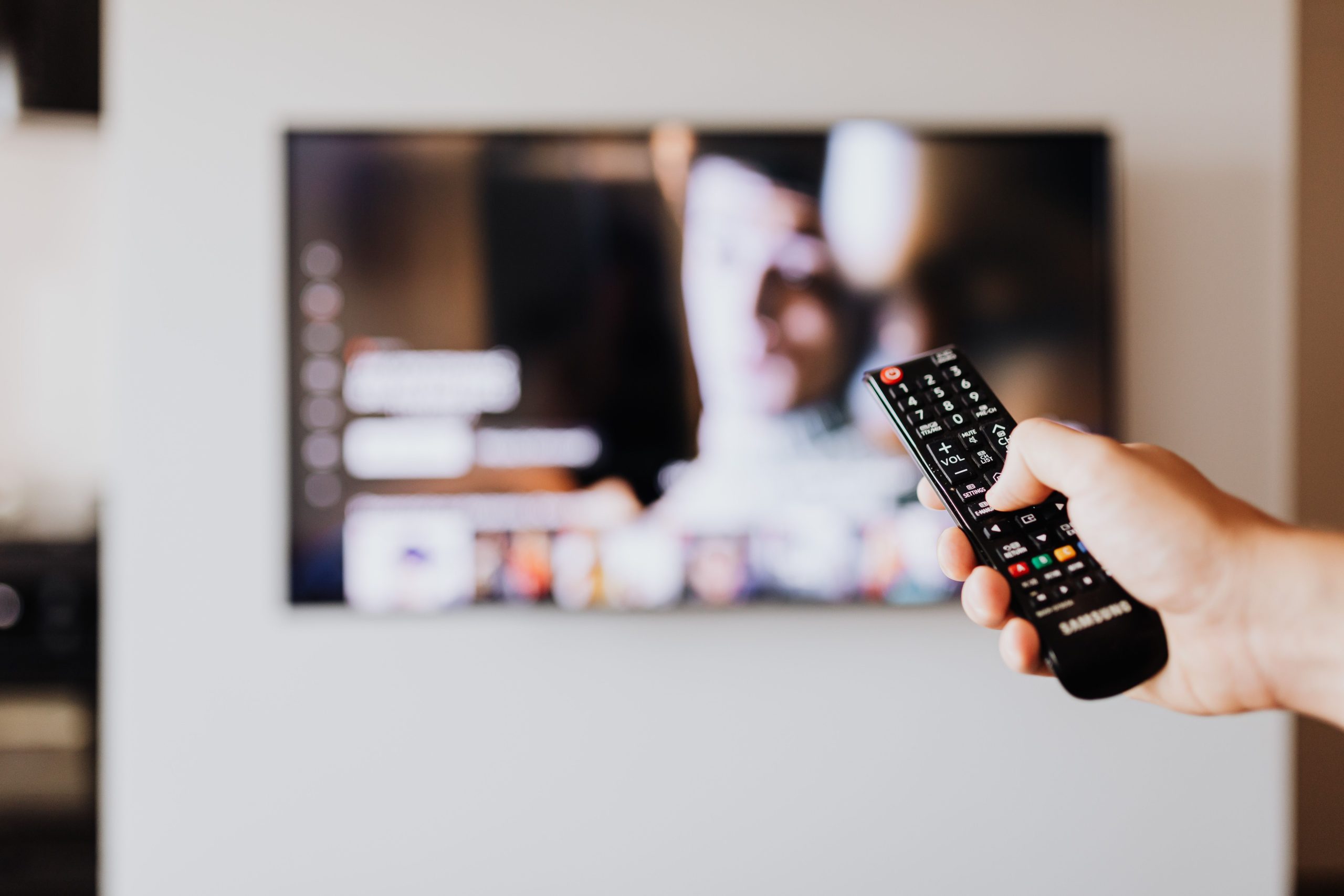 Personne utilisant une télécommande devant la télévision