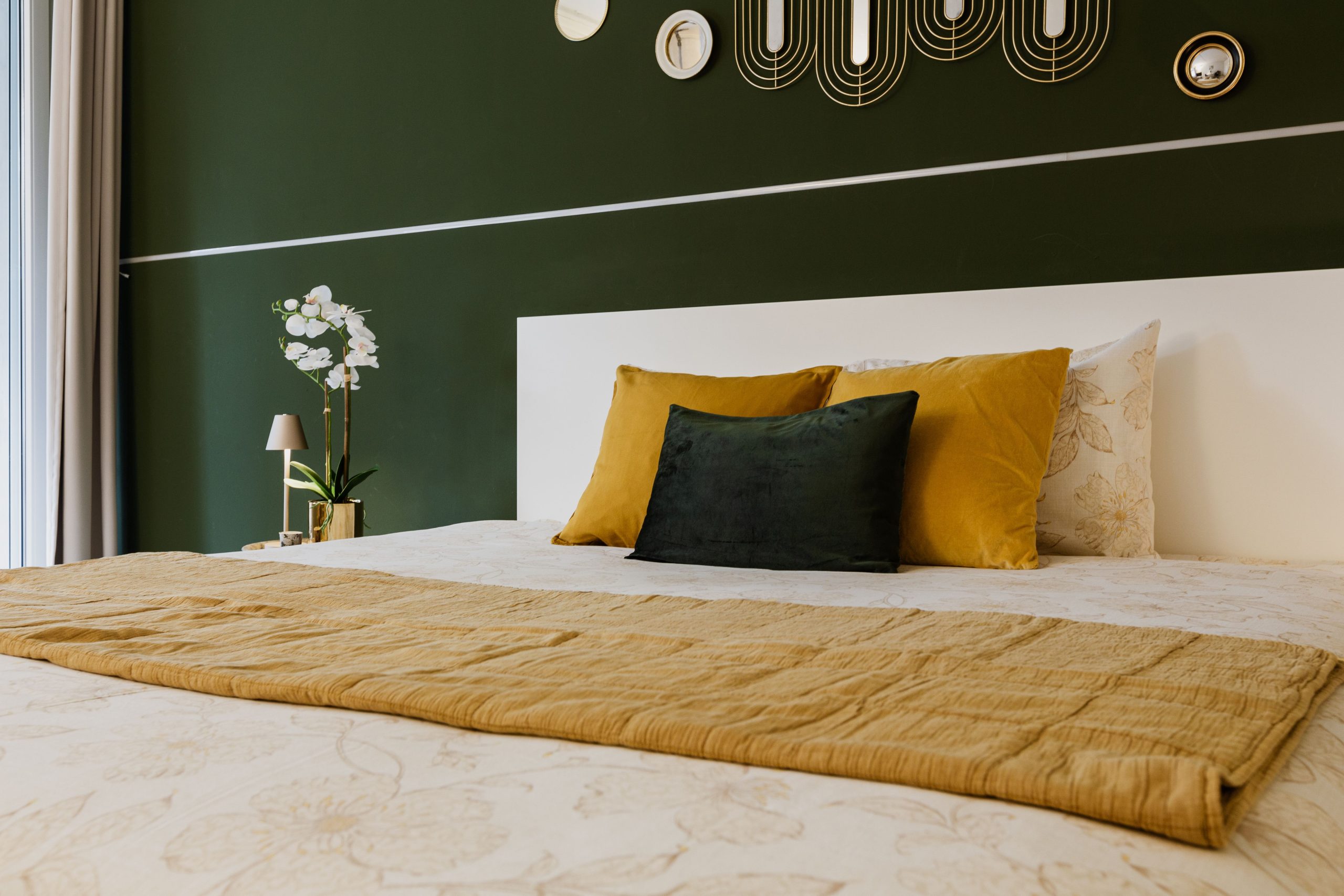 Chambre verte avec coussins jaunes et art mural géométrique